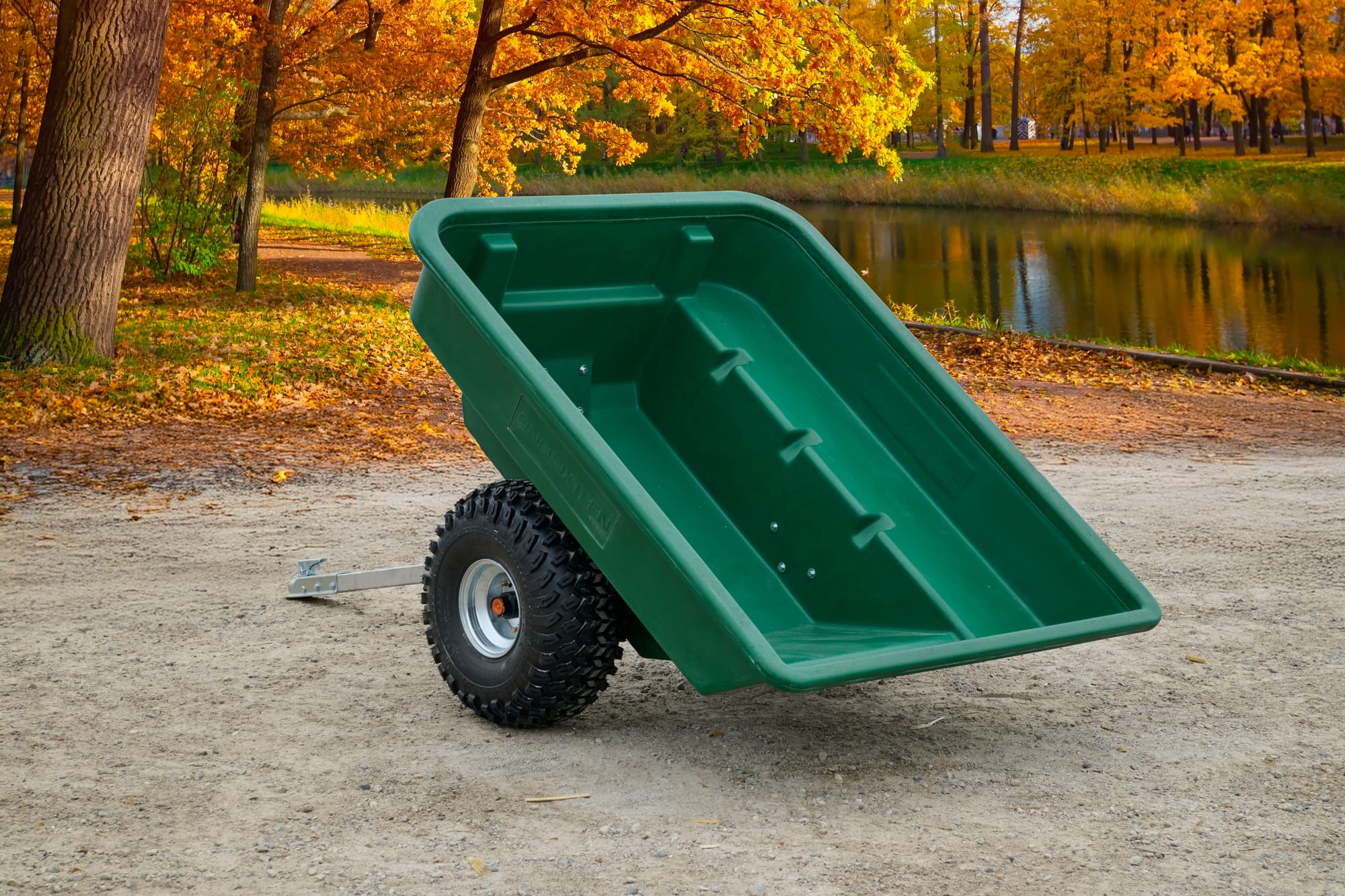 ATVCG ATV trailer green plastic tub tilted upward showing dump position, single wheel view